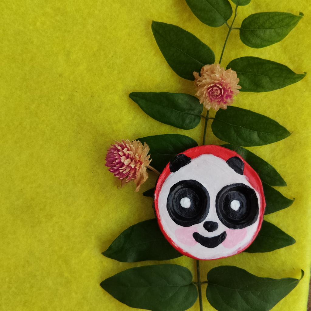Panda-themed round magnet on a yellow background with green leaves and pink flowers - Sustainable Home Decor