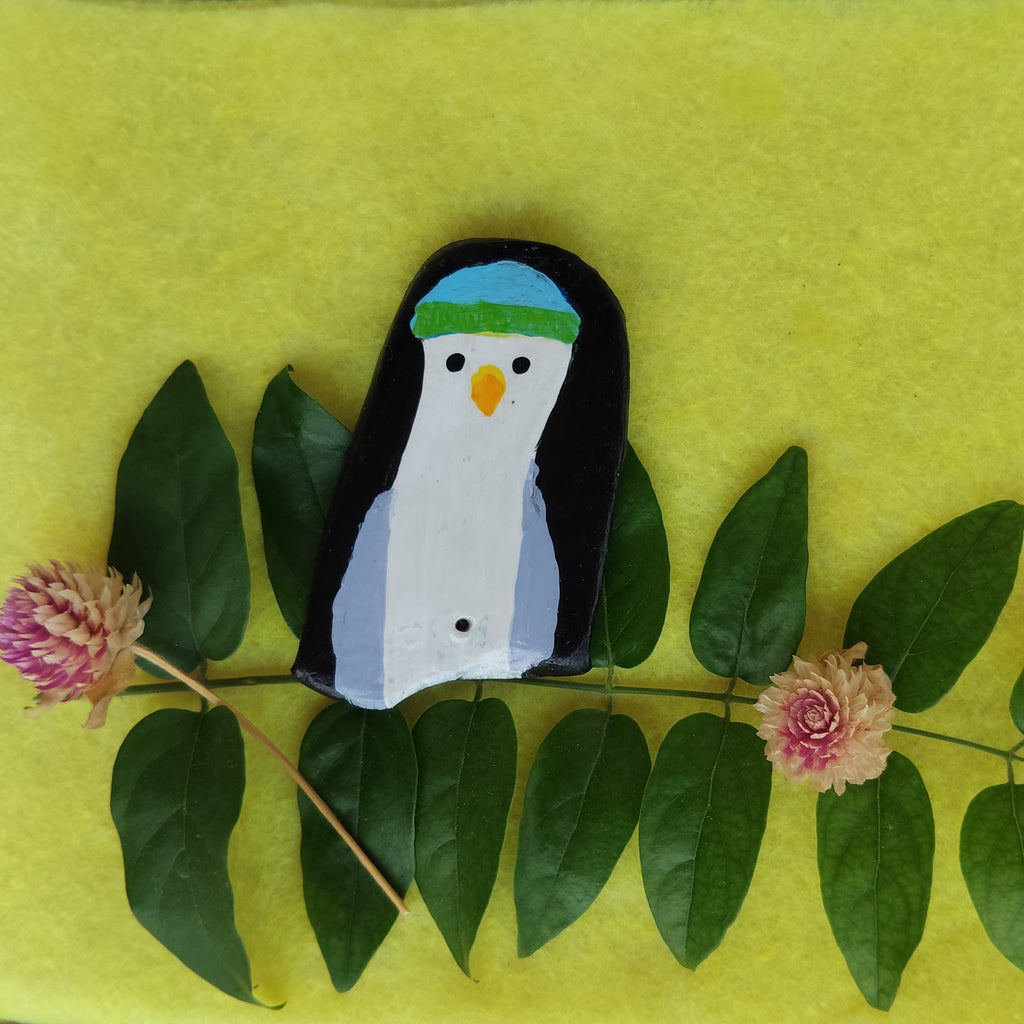 Penguin-shaped object on a green background with leaves and flowers - Sustainable Home Decor