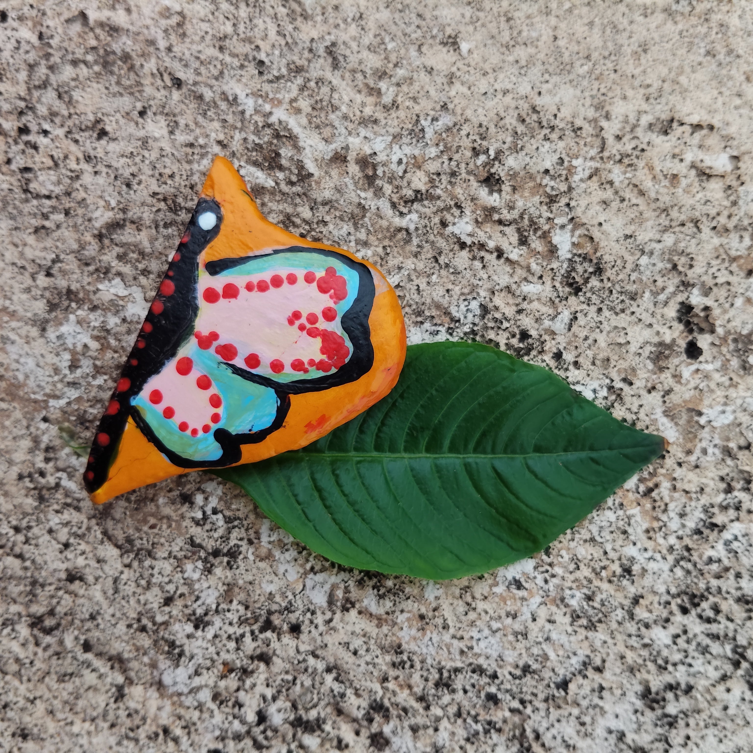 Colorful butterfly-shaped magnet on a green leaf with a textured surface background - Sustainable Home Decor & Upcycled Glass