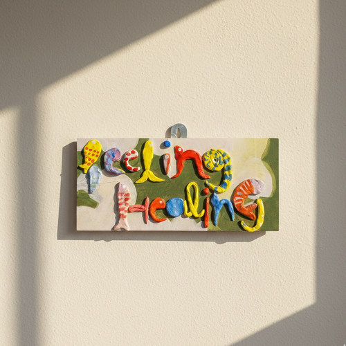 Vibrant aesthetic art 'Feeling Healing' sign hand-crafted on a wooden base hanged on a light background 
