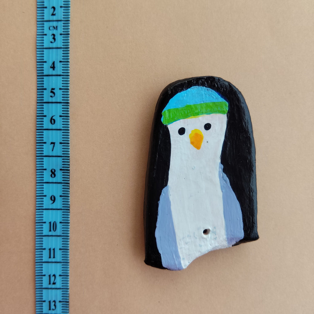Penguin-shaped handmade magnet with a colorful design on a beige background, measured by a blue ruler. - Sustainable Home Decor