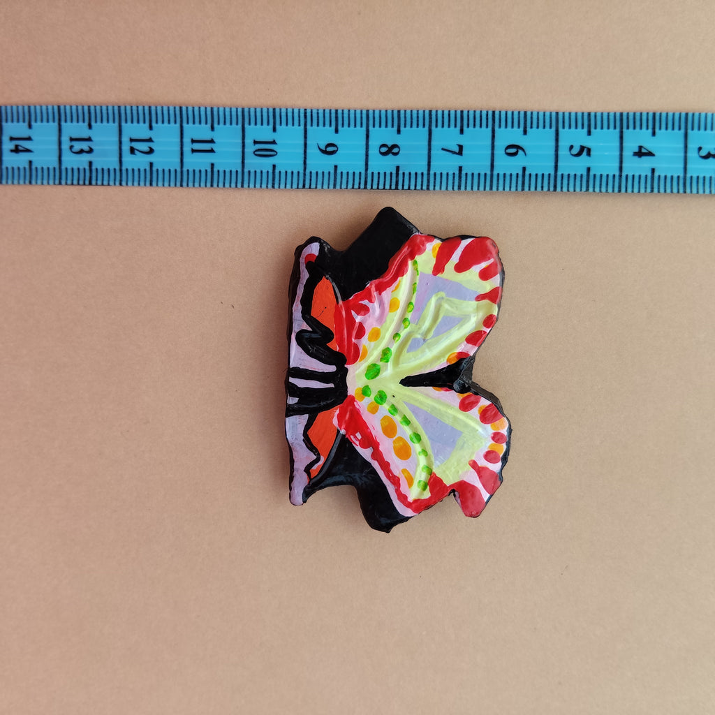Colorful butterfly-shaped object next to a ruler on a beige background - Sustainable Home Decor