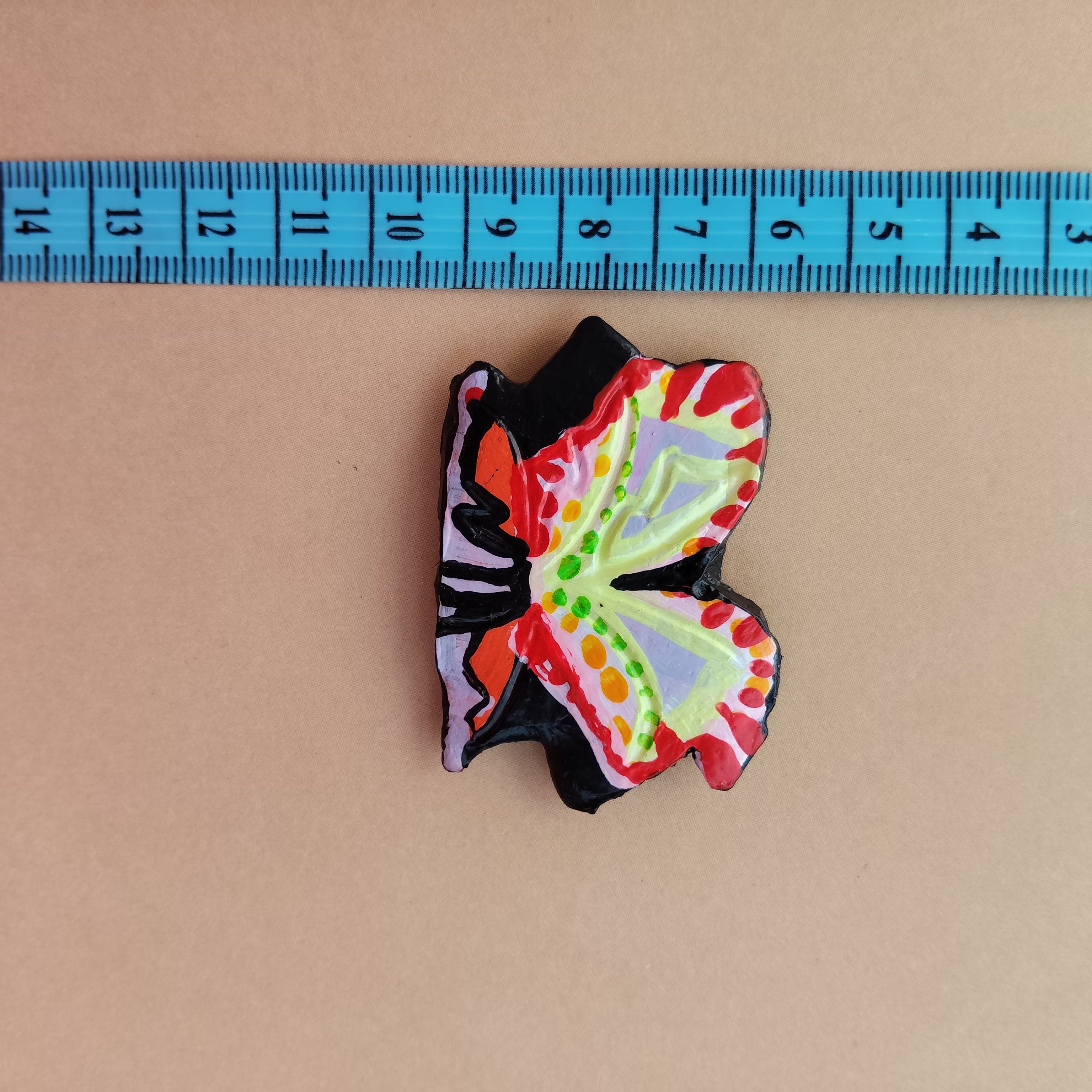 Colorful butterfly-shaped object next to a ruler on a beige background - Sustainable Home Decor & Upcycled Glass