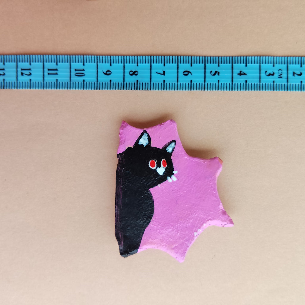 Small pink hand-painted magnet with a black cat design on a beige background, measured by a blue ruler. - Sustainable Home Decor