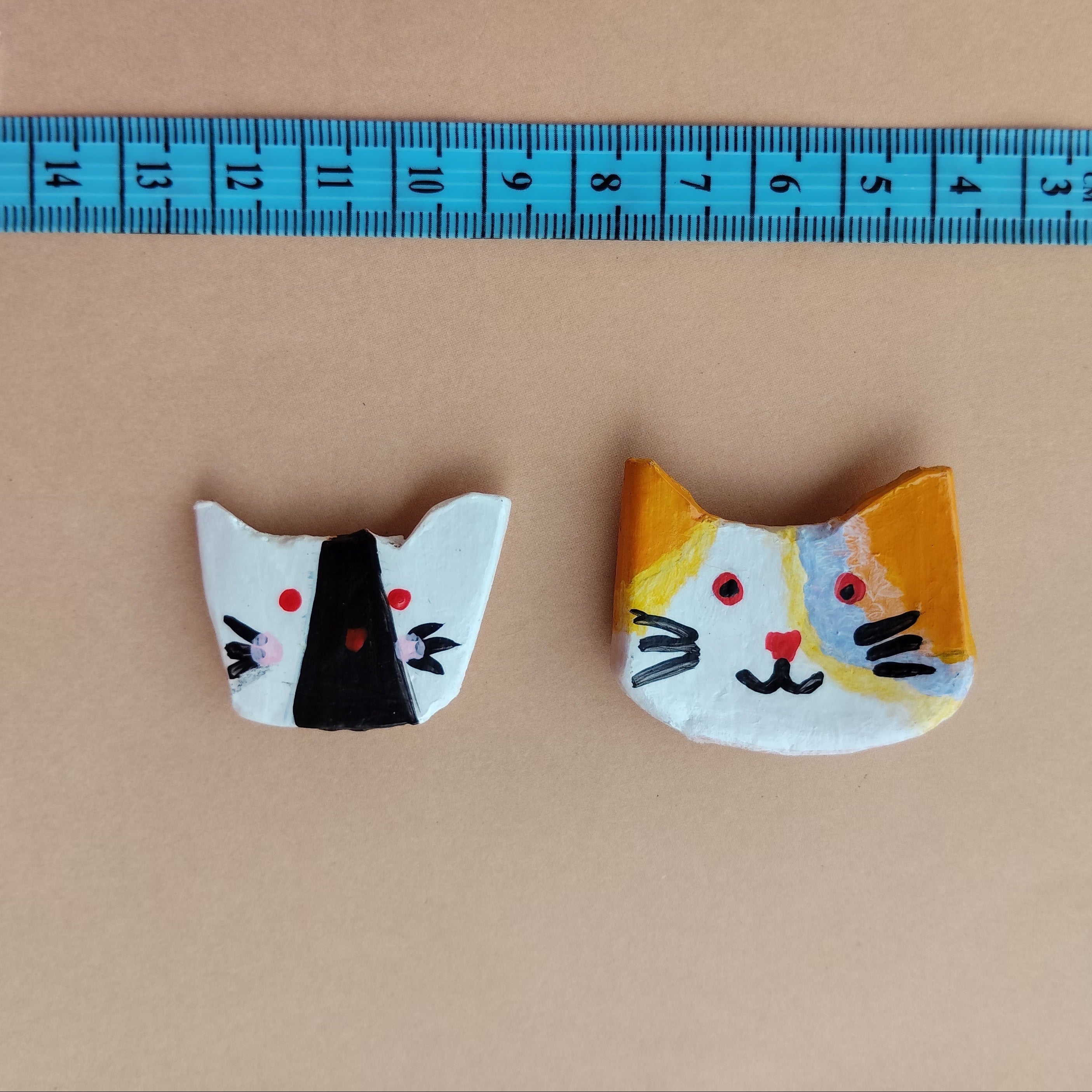 Two crescent-shaped with cat designs next to a ruler on a beige background - Sustainable Home Decor & Upcycled Glass