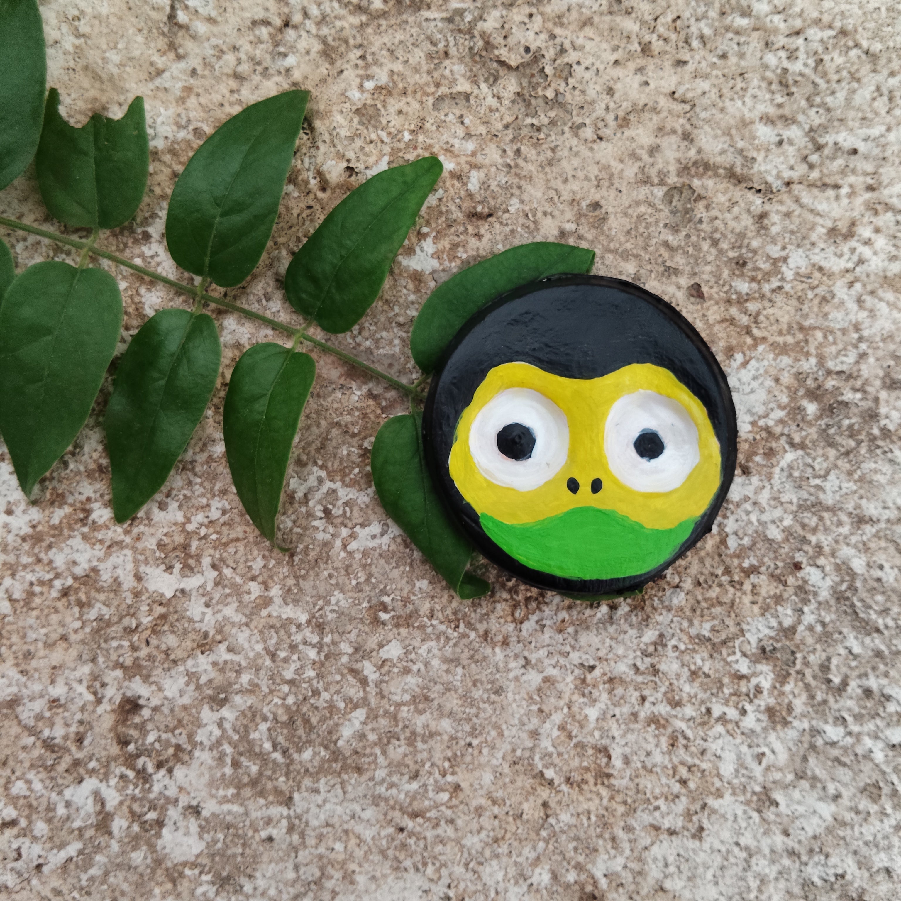 Hand-painted frog face design on a textured surface with leaves. - Sustainable Home Decor & Upcycled Glass