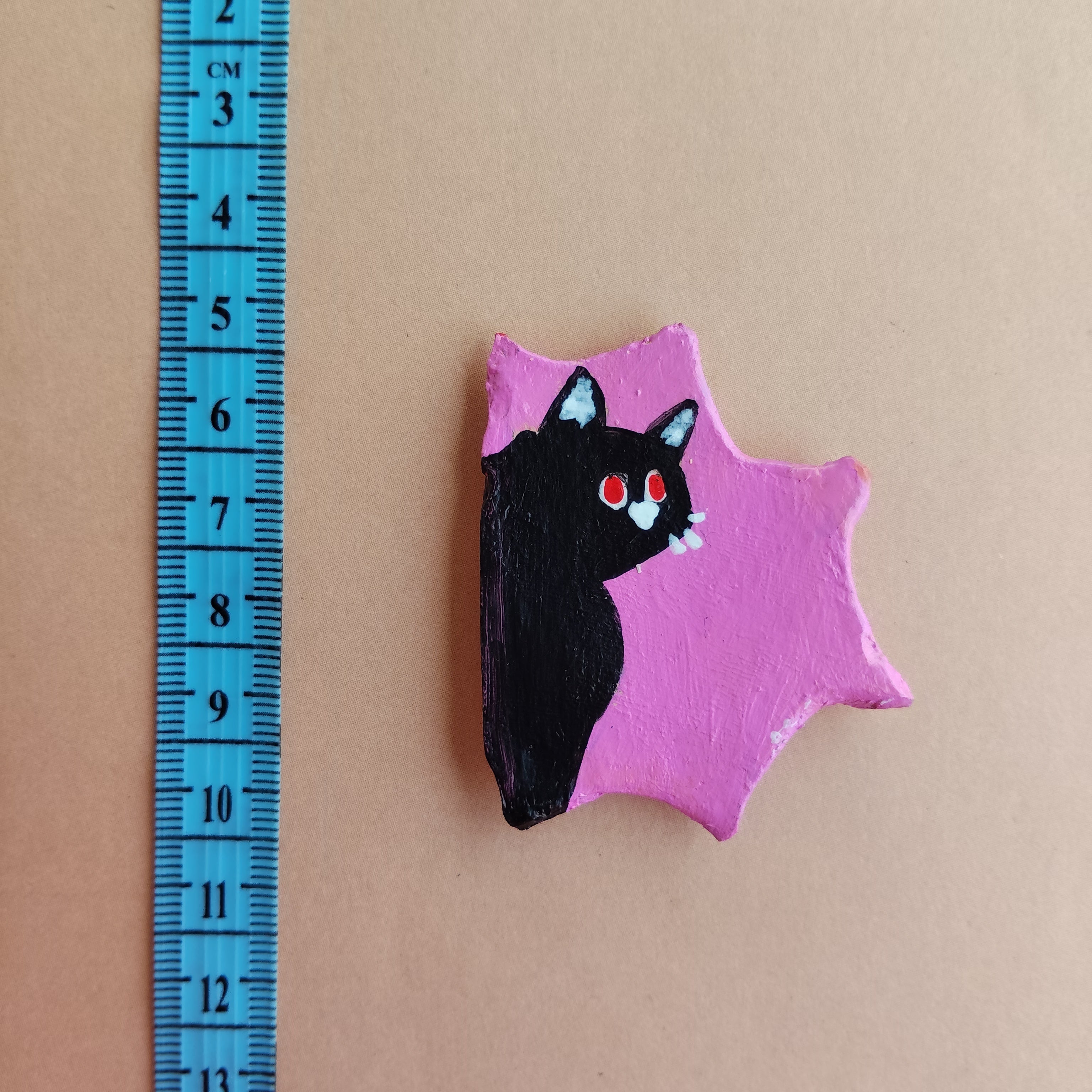 Pink miniature magnet with black cat design on a beige background, measured by a blue ruler. - Sustainable Home Decor & Upcycled Glass