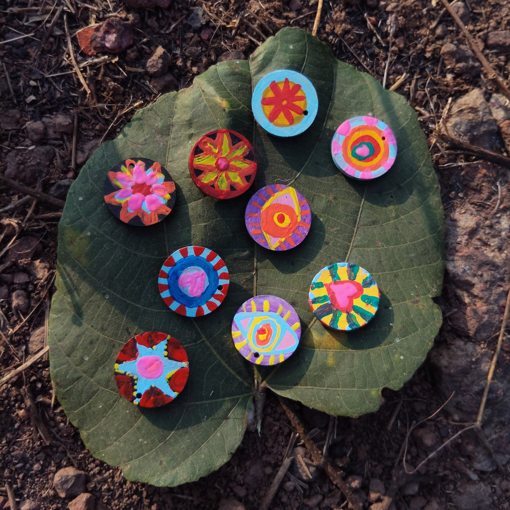 Colorful circular hand-painted miniatures lying randomly on a leaf with a natural background