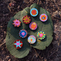 Colorful circular hand-painted miniatures lying randomly on a leaf with a natural background