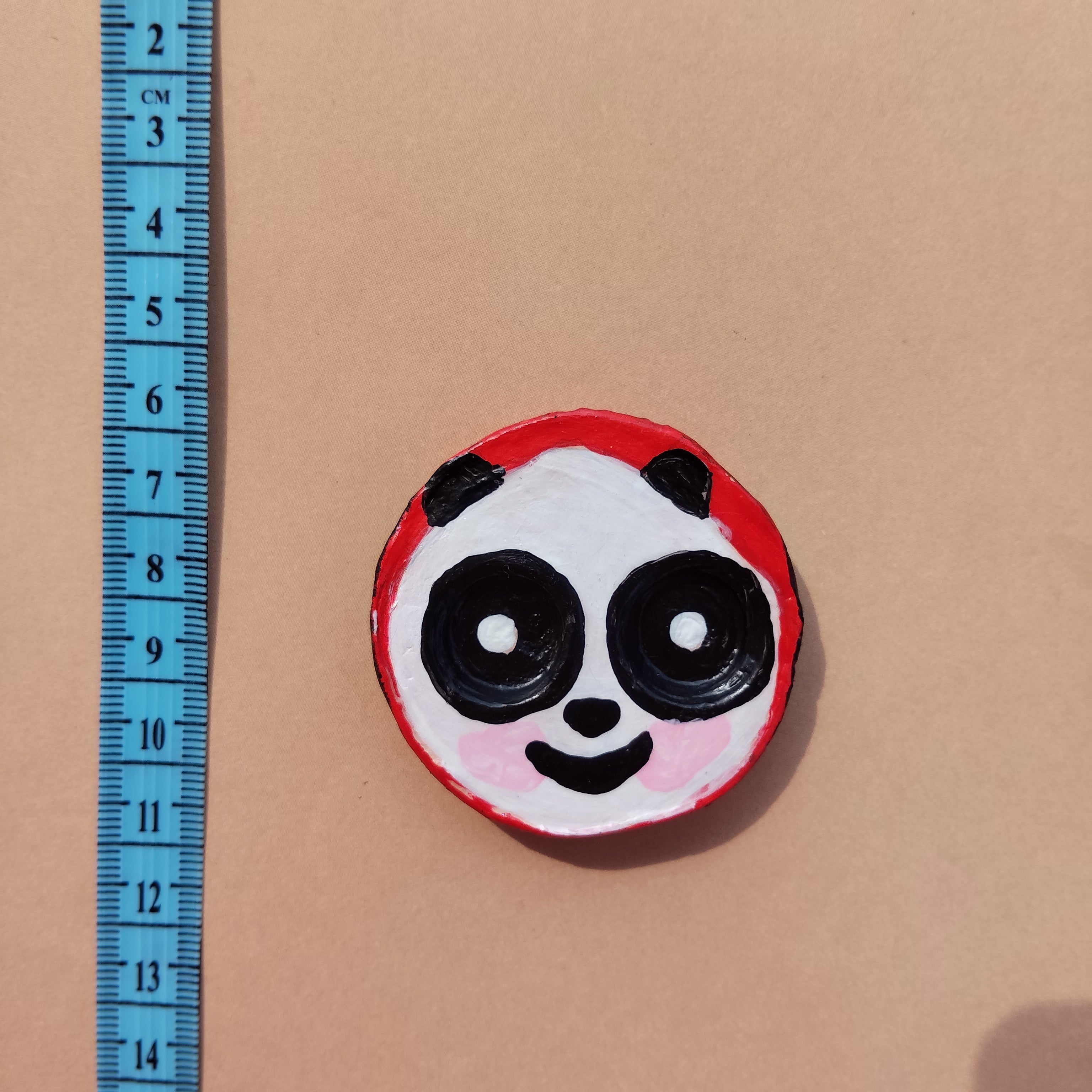 Round object with panda design on a beige background, measured by a blue ruler. - Sustainable Home Decor & Upcycled Glass