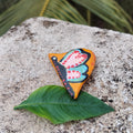 Colorful butterfly-shaped magnet on a green leaf with a natural background.