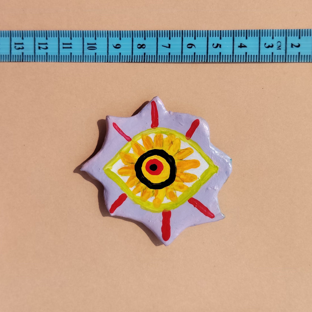 Artistic hand-painted eye with a colorful design next to a ruler on a beige background. - Sustainable Home Decor