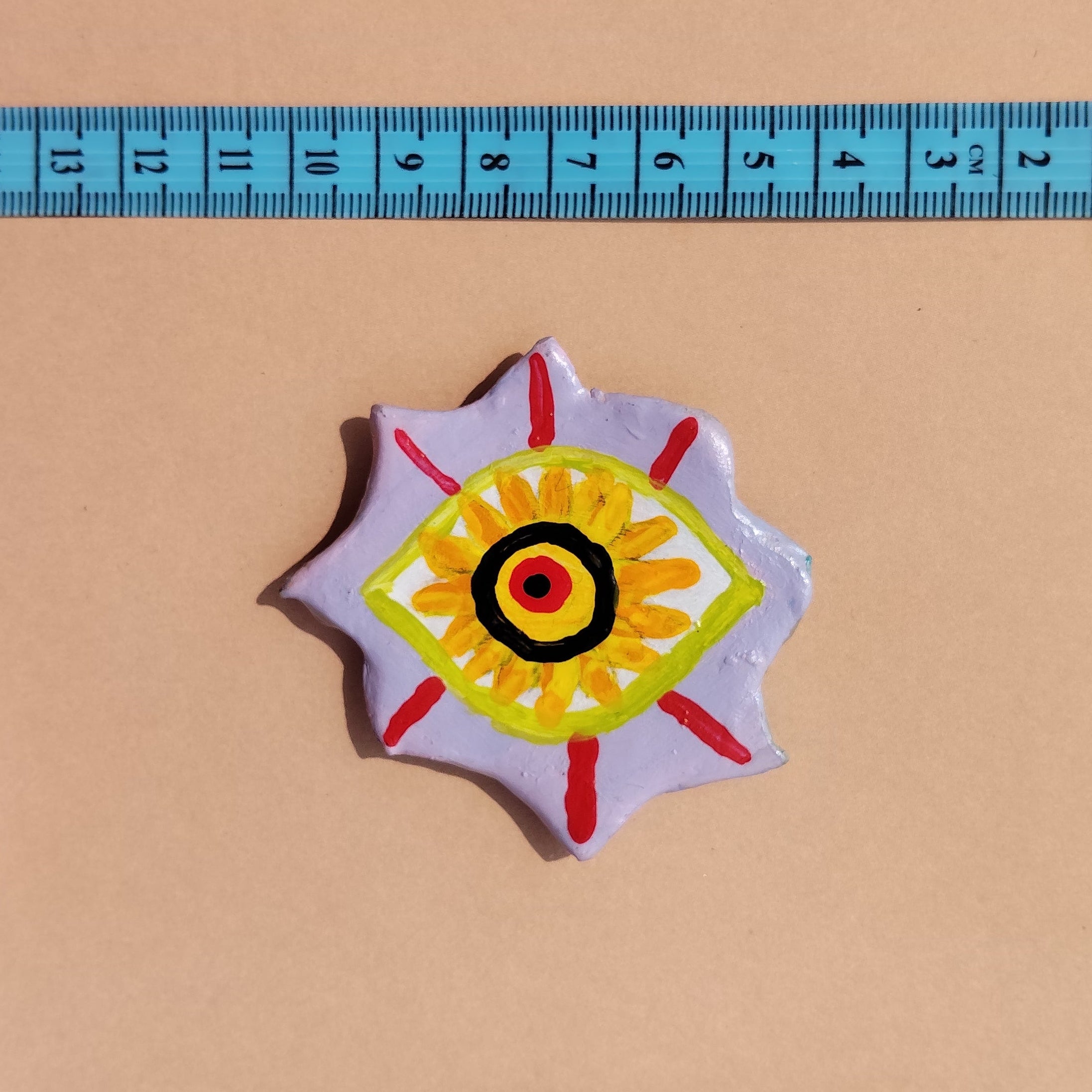 Artistic hand-painted eye with a colorful design next to a ruler on a beige background. - Sustainable Home Decor & Upcycled Glass