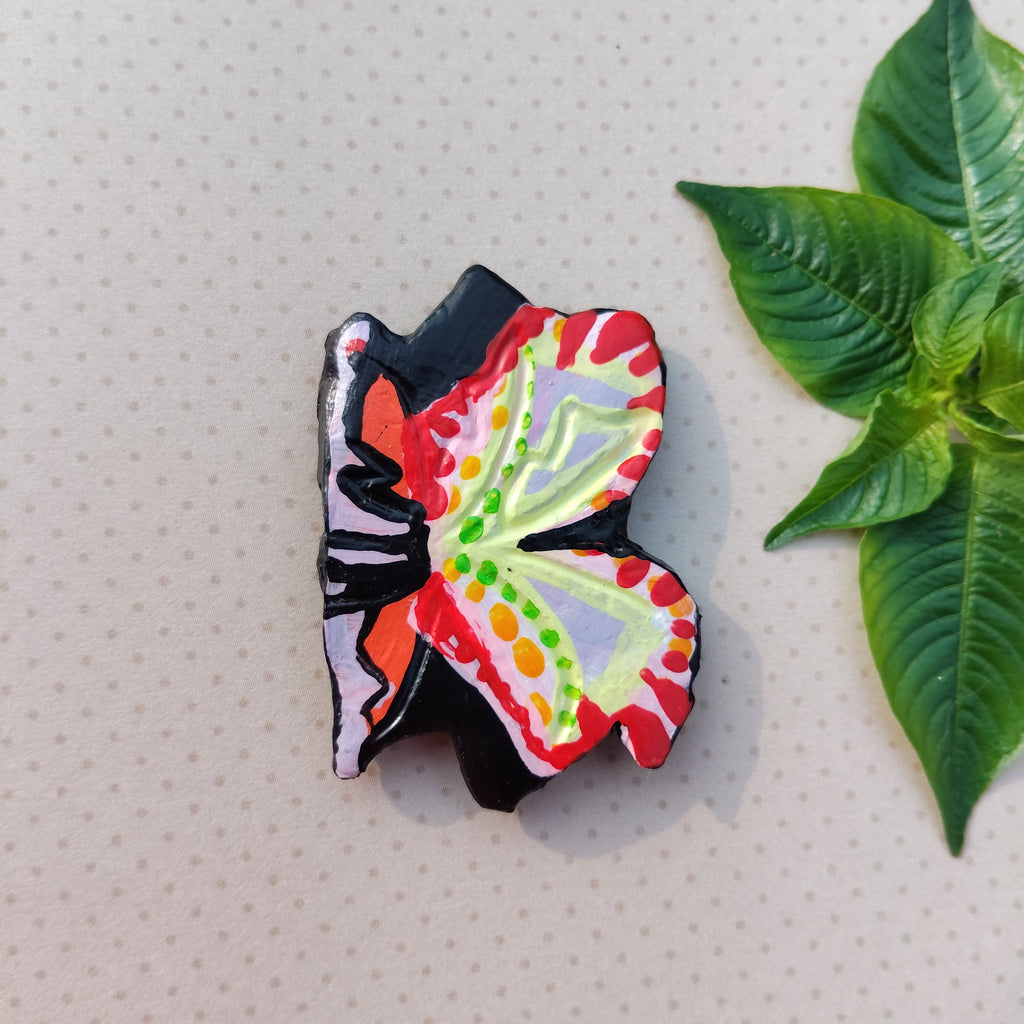 Colorful butterfly-shaped magneton a textured surface with a green leaf. - Sustainable Home Decor