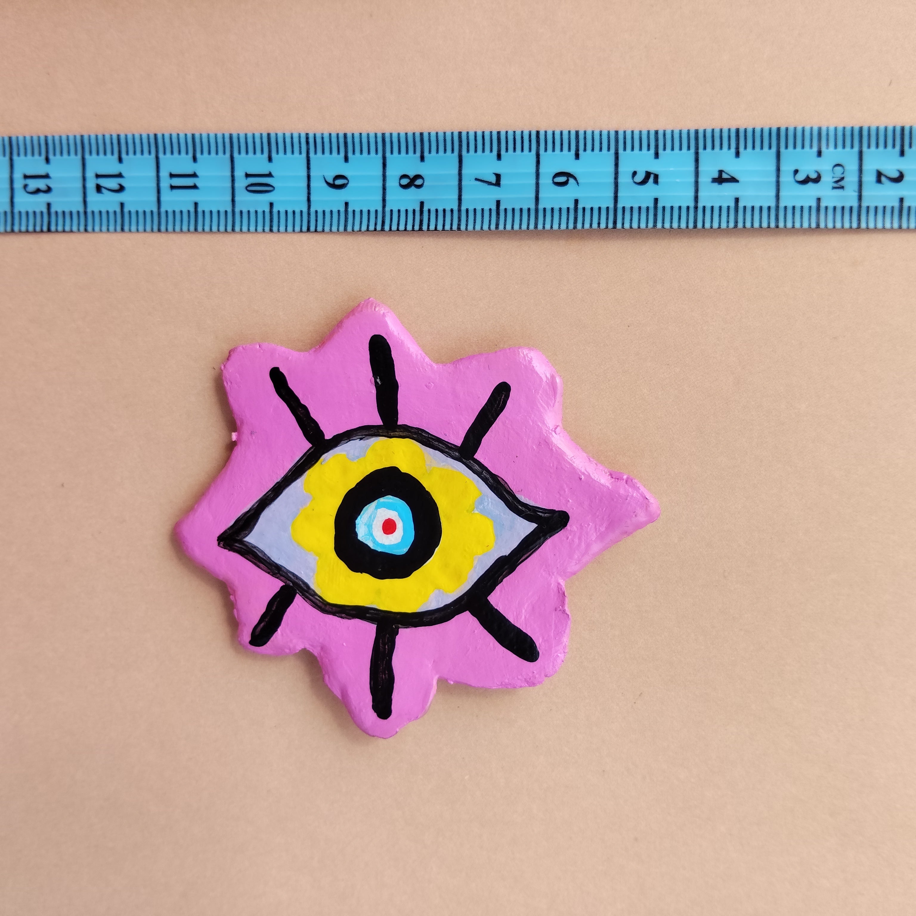 Artistic miniature magnet piece with eye design on a pink background, measured against a ruler. - Sustainable Home Decor & Upcycled Glass