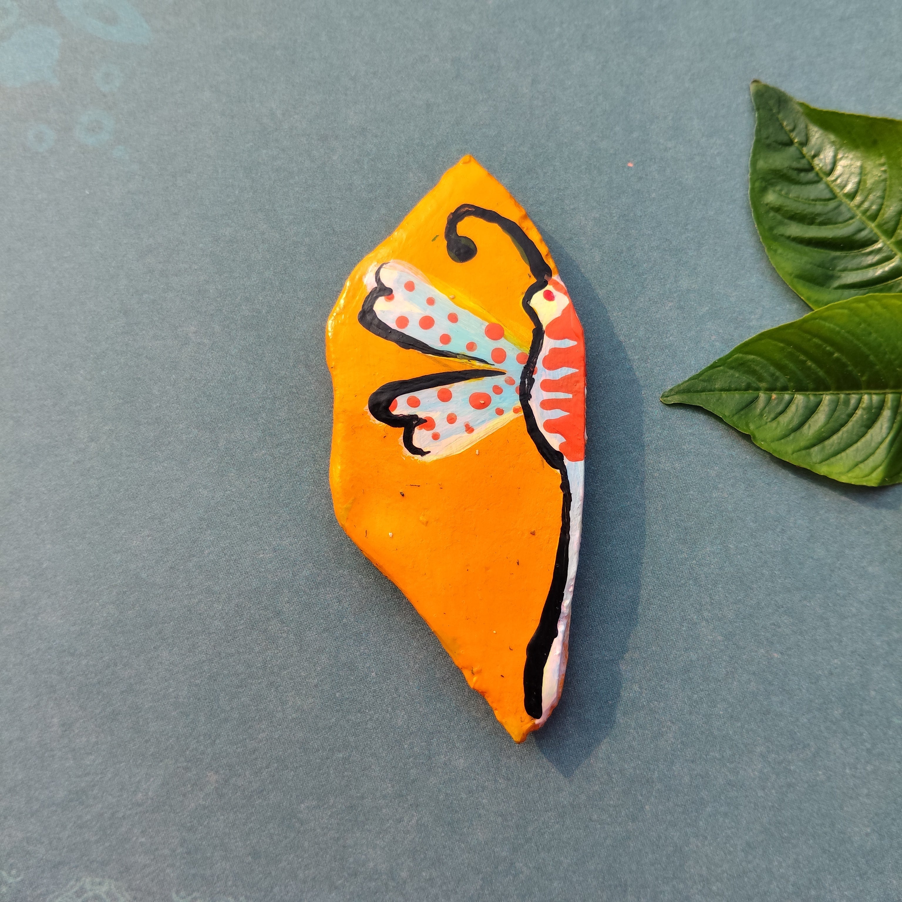 Decorative leaf-shaped handmade magnet with a colorful fly design on a gray background - Sustainable Home Decor & Upcycled Glass