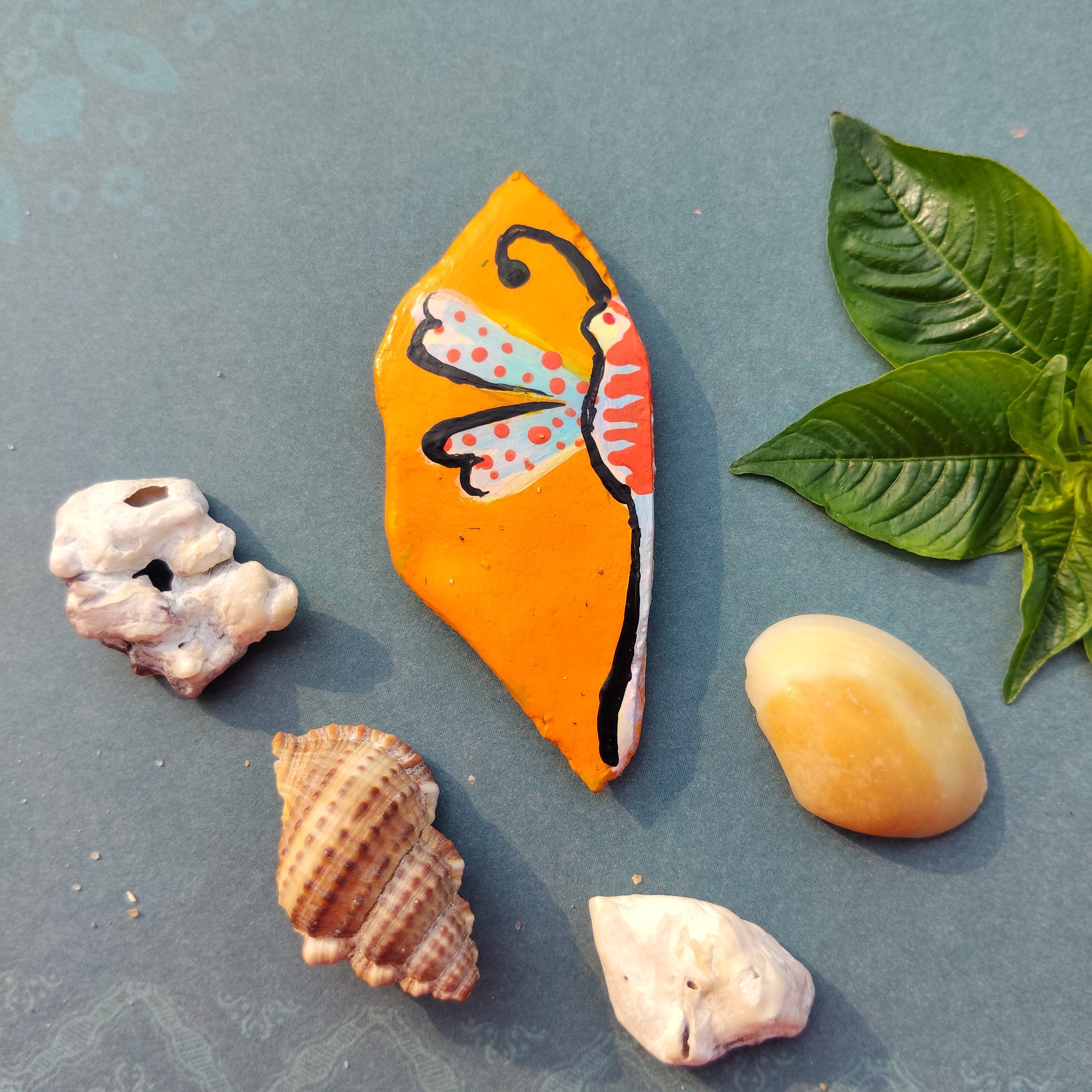 Mustard colored magnet in leaf shape lying on grey background with green leaves and shells around. - Sustainable Home Decor & Upcycled Glass