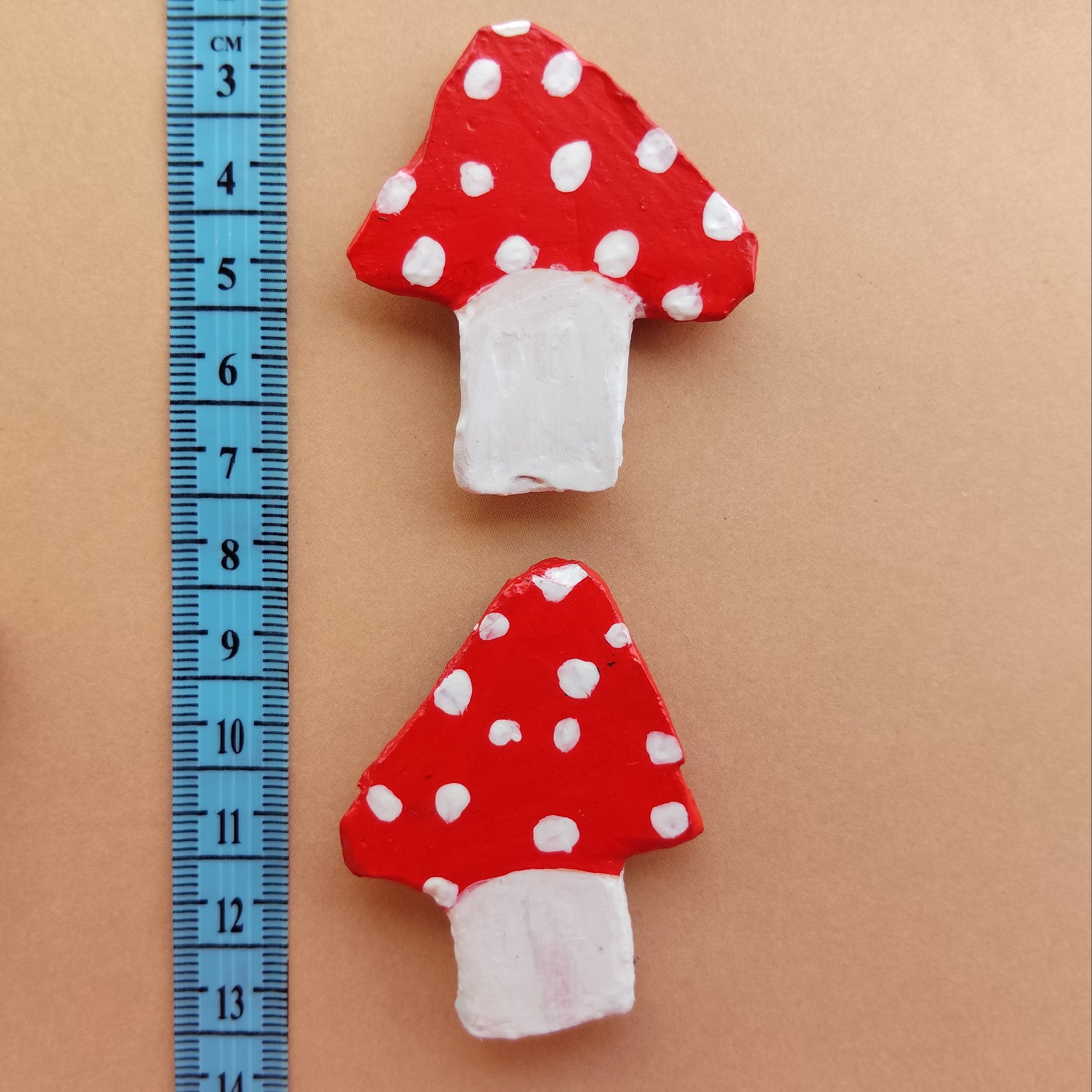 Two mushroom shaped handmade magnet lying on beige background with blue measuring ruler. - Sustainable Home Decor & Upcycled Glass