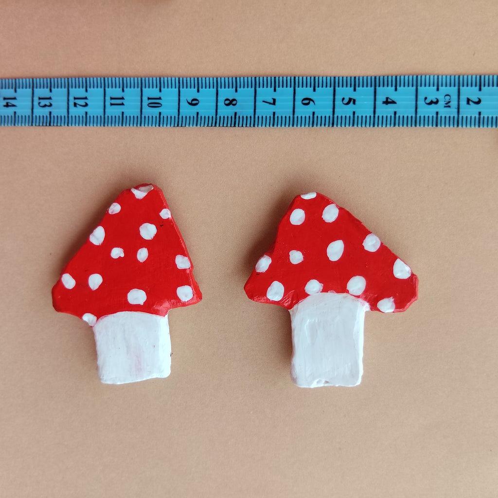 Two red mushroom-shaped art with white polka dots on a beige background, measured by a blue ruler. - Sustainable Home Decor