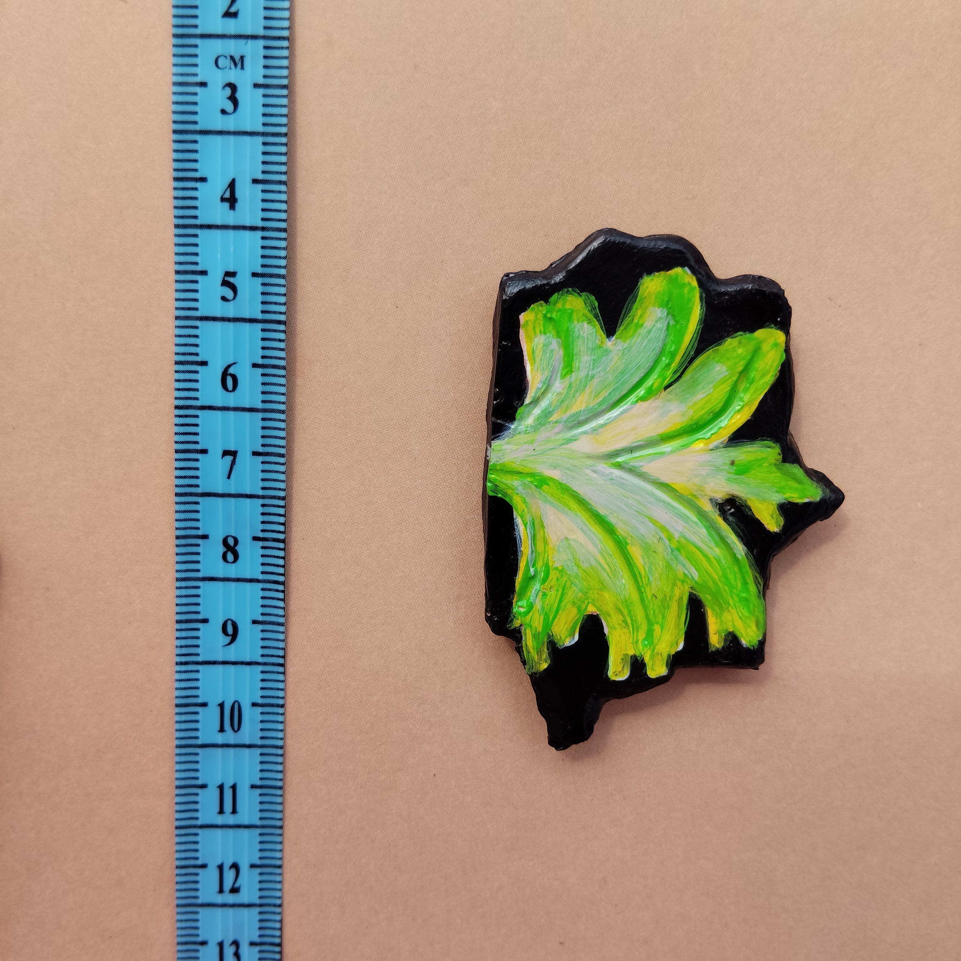 Green leaf-shaped magnet next to a ruler on a brown background - Sustainable Home Decor & Upcycled Glass