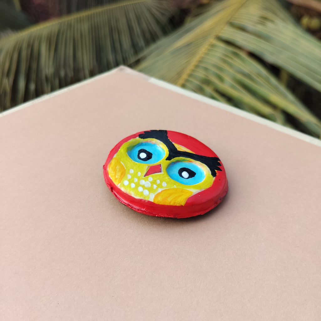 Colorful owl-shaped object on a pink surface with green leaves in the background - Sustainable Home Decor