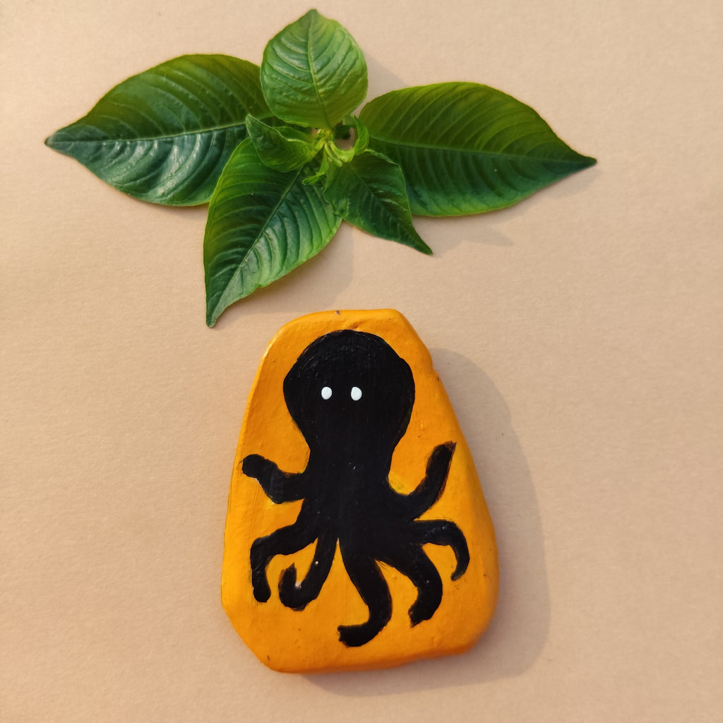 Mustard eco-friendly magnet with black octopus design next to a green leaf on a beige background - Sustainable Home Decor