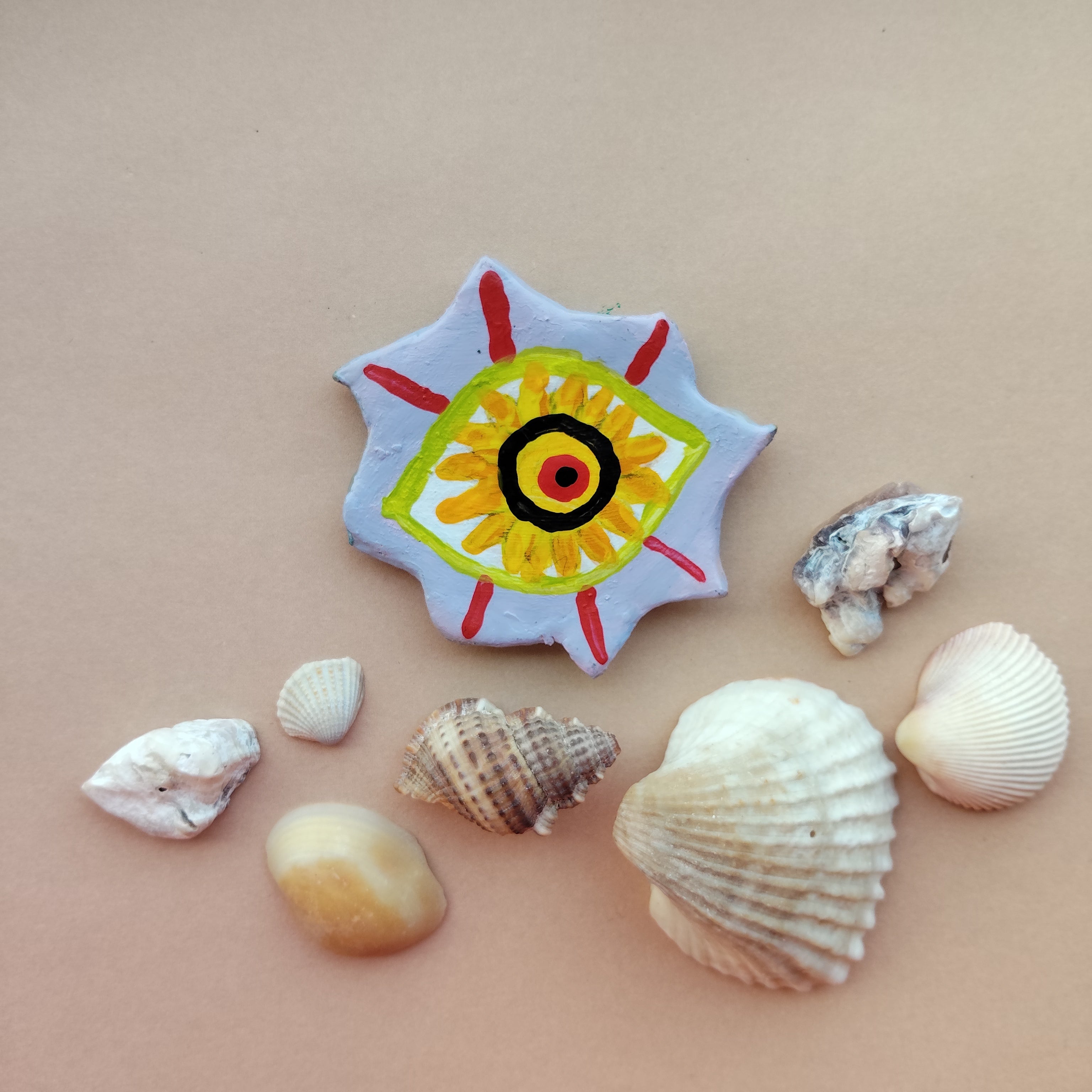 Artistic magnet with a colorful design surrounded by various shells on a beige background. - Sustainable Home Decor & Upcycled Glass