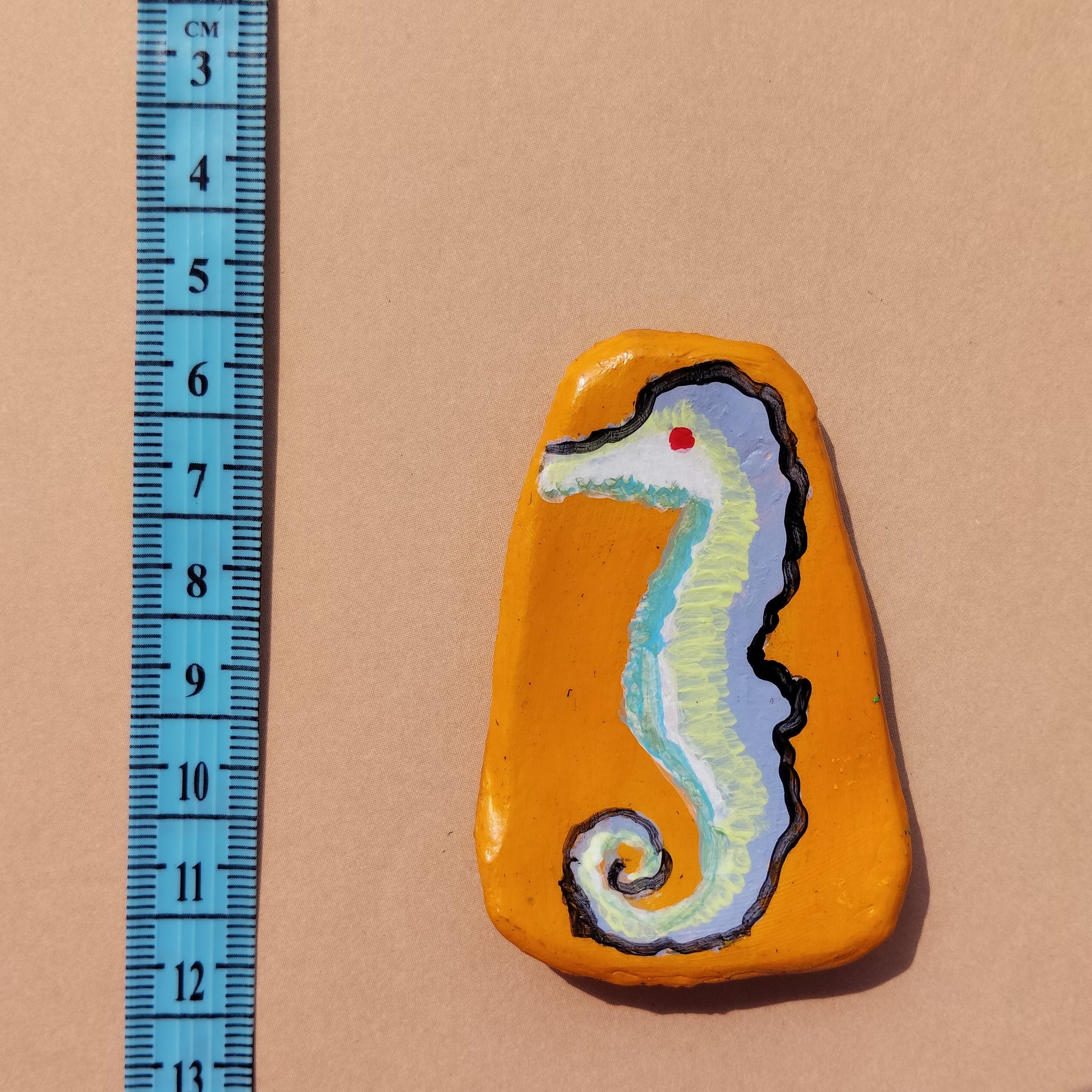 Artistic mini magnet with a painted design of a seahorse on a beige background, accompanied by a ruler for scale. - Sustainable Home Decor & Upcycled Glass
