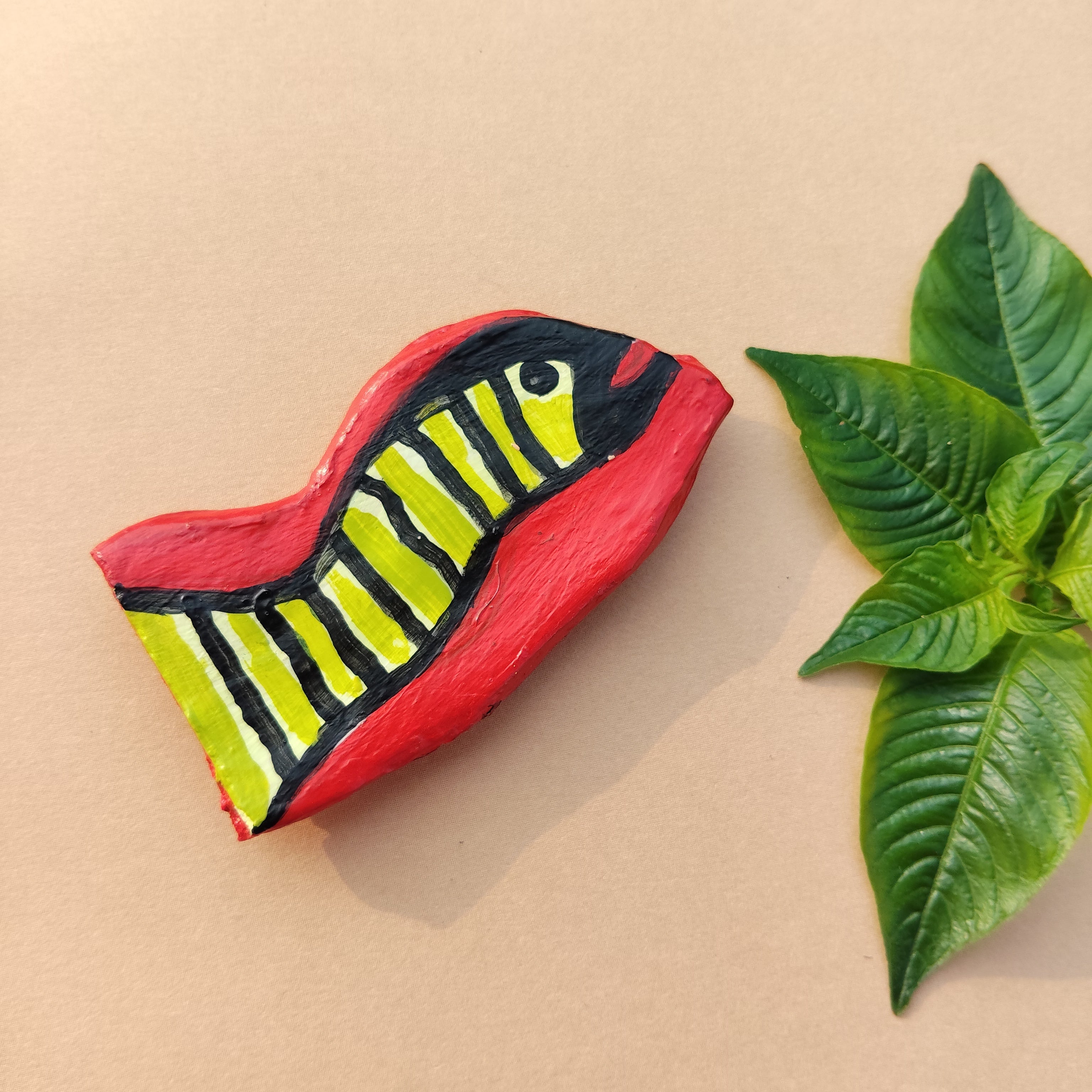 Designer handcrafted shaped like a snake with red, yellow, and black patterns on a beige background with a green leaf. - Sustainable Home Decor & Upcycled Glass