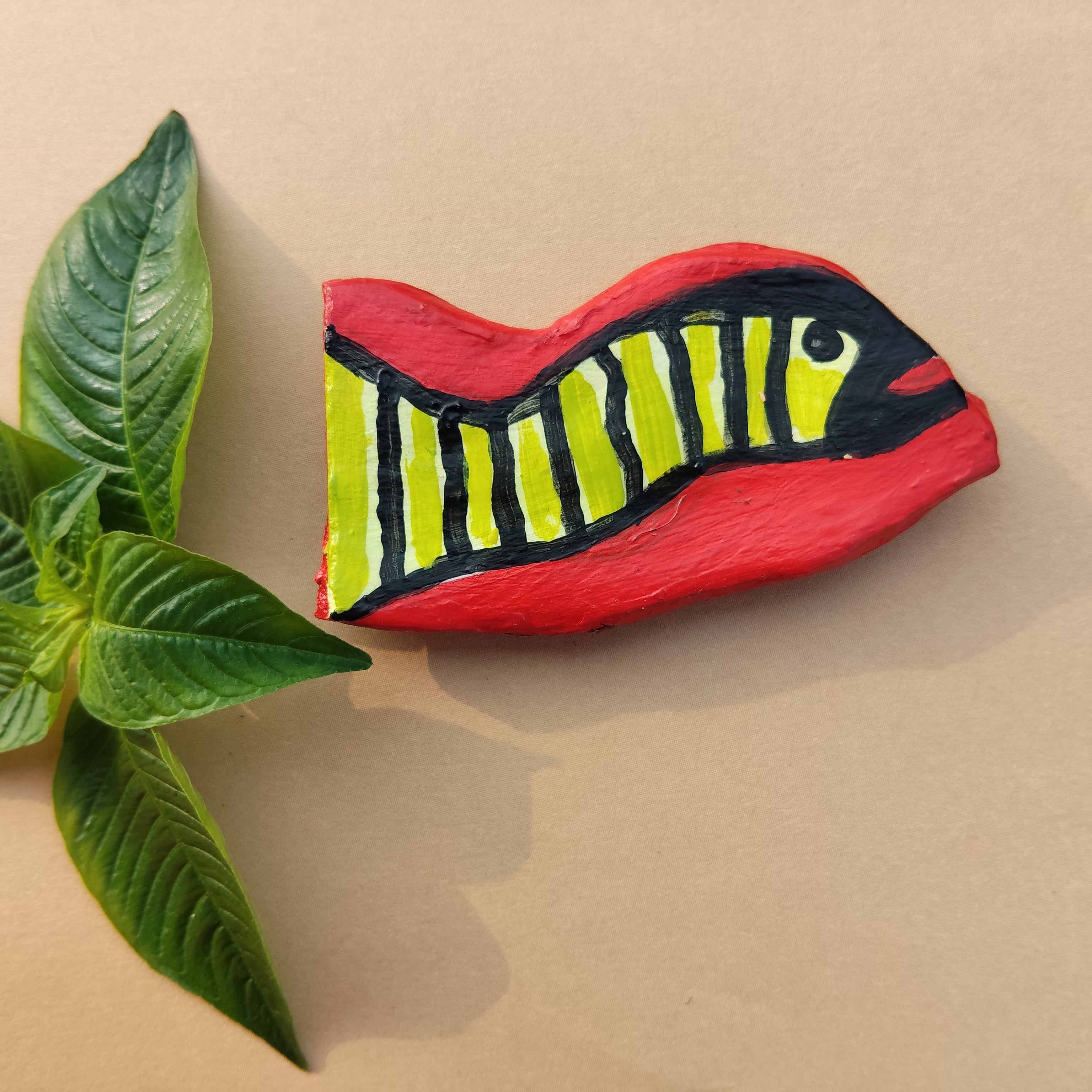 Decorative free hand hand-crafted magnet with snake design next to a green leaf on a beige background - Sustainable Home Decor & Upcycled Glass