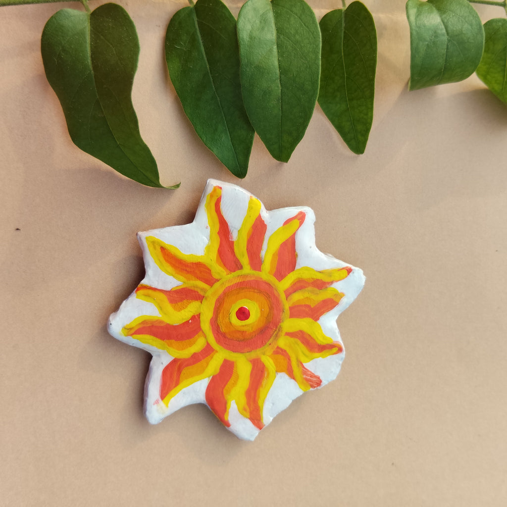 Colorful sun-shaped object on a beige background with green leaves - Sustainable Home Decor