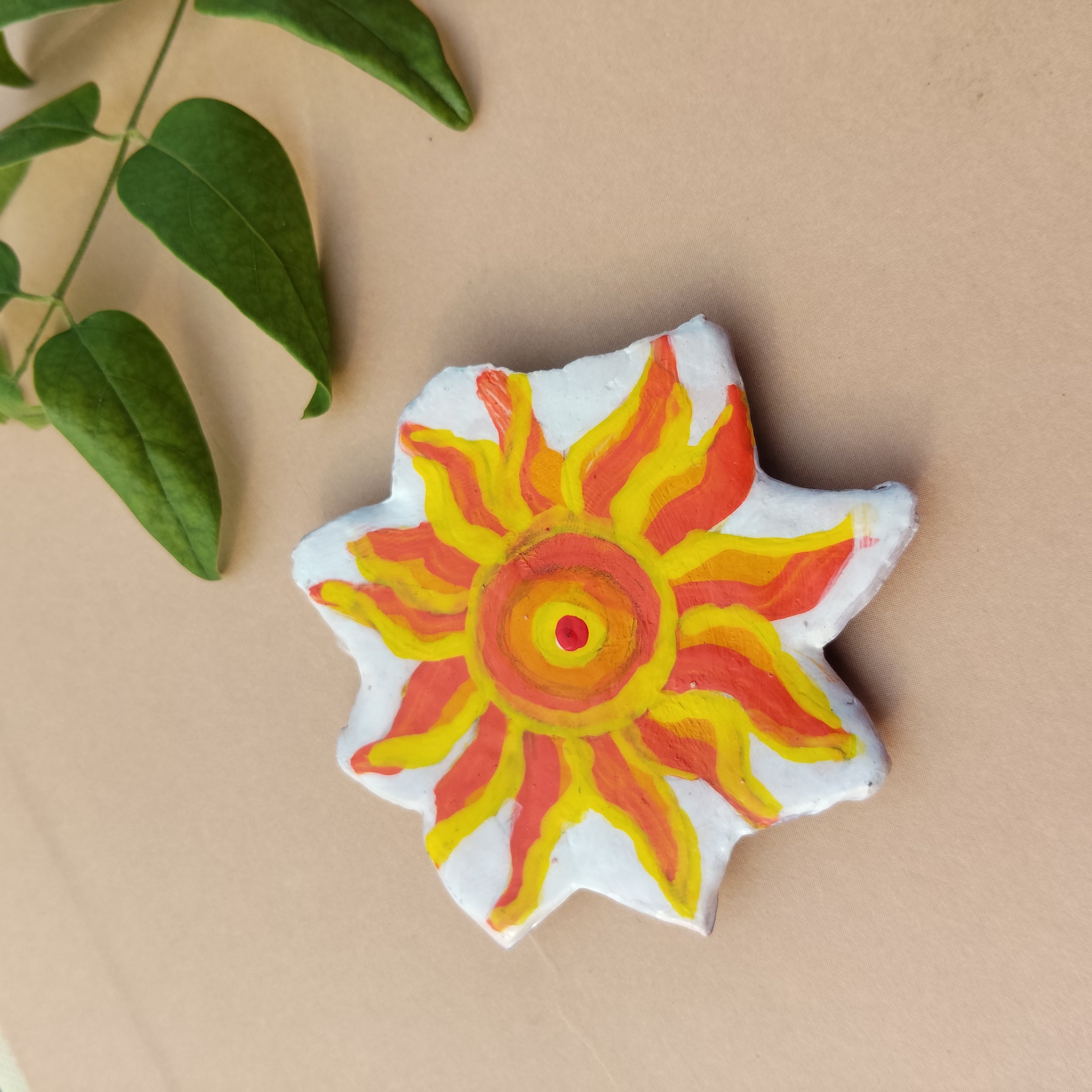 Decorative sun-shaped object with red and yellow design on a beige background - Sustainable Home Decor & Upcycled Glass