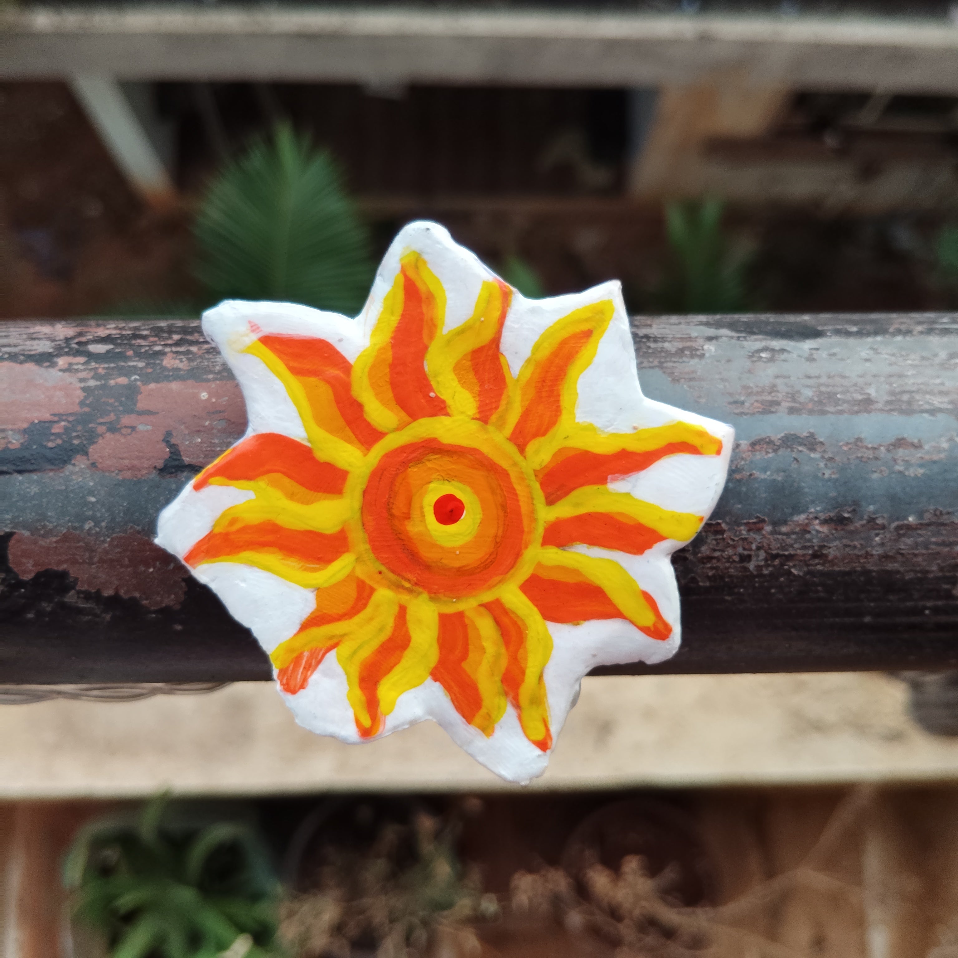 Sun-shaped object with a yellow and orange design on a wooden surface - Sustainable Home Decor & Upcycled Glass
