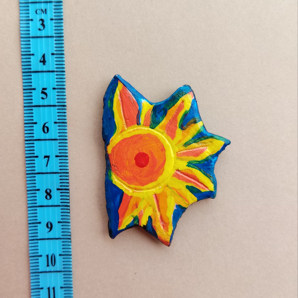 Colorful sun-shaped object with a ruler for scale on a beige background - Sustainable Home Decor