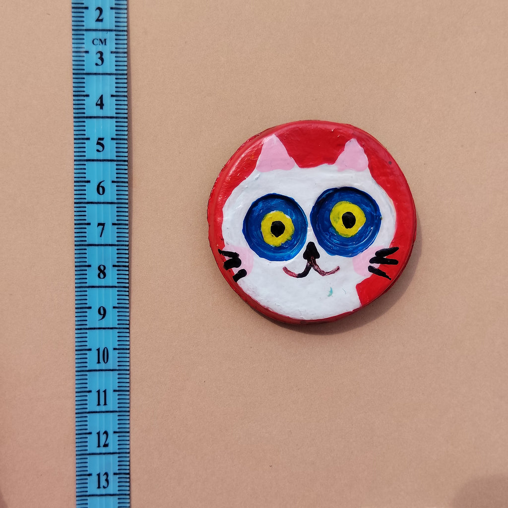 Round magnet with cat face design lying on beige background with bue measuring ruler - Sustainable Home Decor