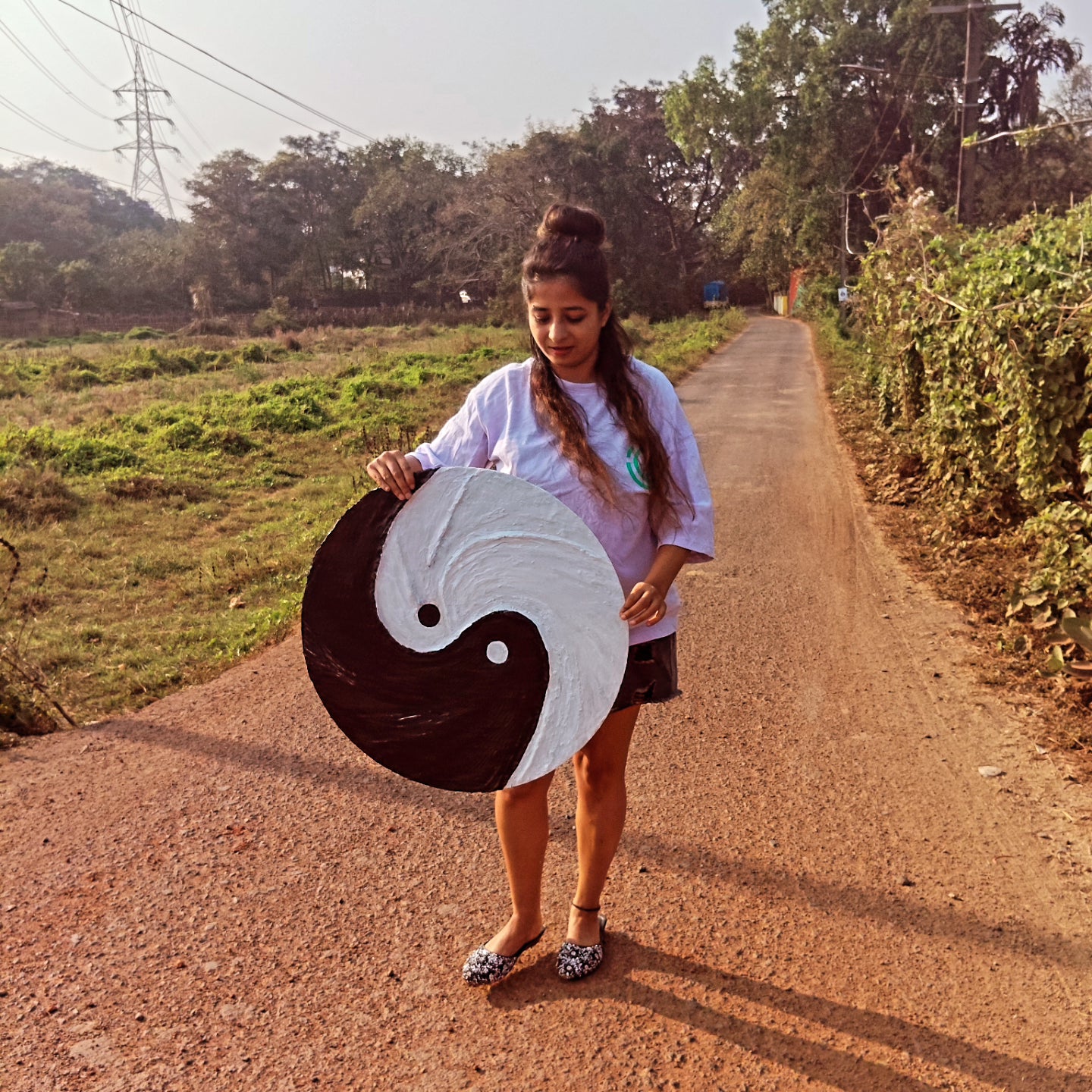 A girl proudly showing her hand-crafted textured yin yang symbol wall art made using sustainable materials.